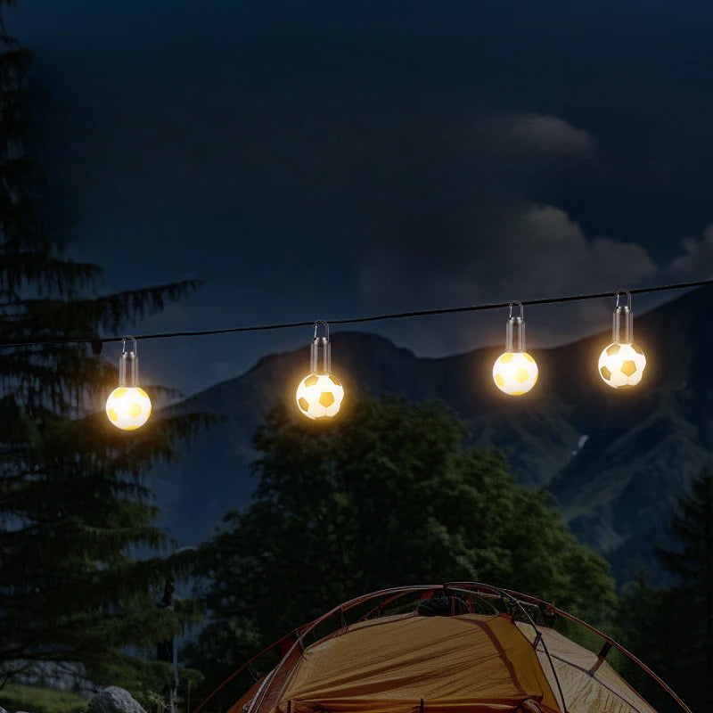 Guirnalda de luces LED con forma de balón de fútbol colgadas al aire libre, ideal para camping y decoración temática deportiva.