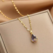 Collar largo con dije de gota de agua en piedra morada montado en flores metálicas